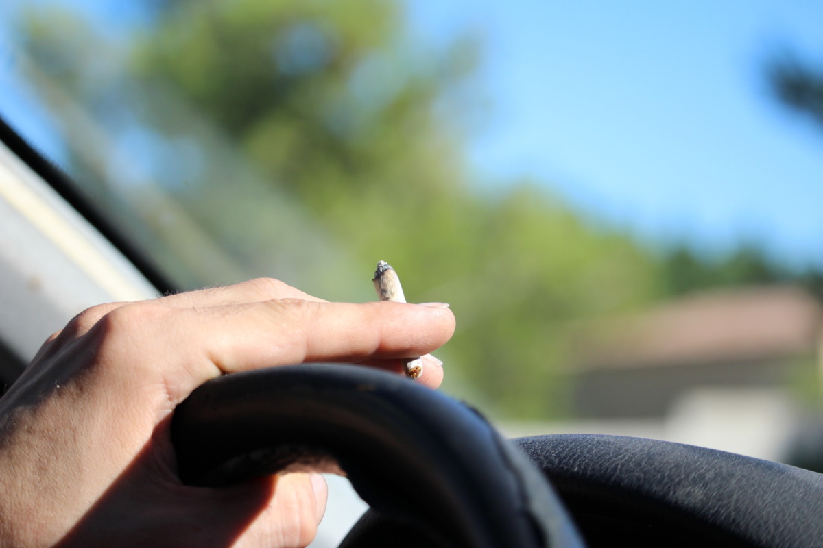 運転中に大麻を吸う男性の手