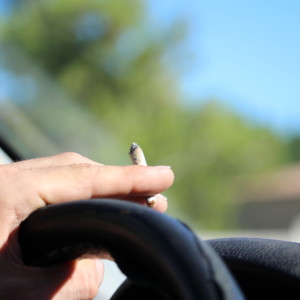運転中に大麻を吸う男性の手